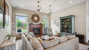 Living area featuring wood finished floors, a glass covered fireplace, recessed lighting, a chandelier, and baseboards