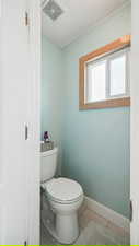 Bathroom with toilet, tile patterned flooring, baseboards, and a textured ceiling