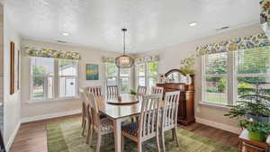 Dining room with a textured ceiling, wood finished floors, baseboards, a chandelier, and recessed lighting