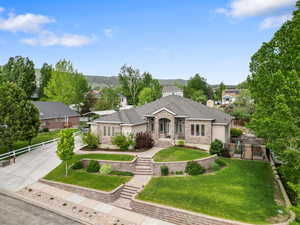 View of front facade with stucco siding, concrete driveway, and roof with shingles