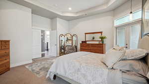 Carpeted bedroom featuring a towering ceiling, baseboards, a tray ceiling, and access to outside