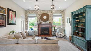 Living room featuring a glass covered fireplace, wood finished floors, recessed lighting, and a chandelier