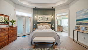 Bedroom with light carpet, multiple windows, access to exterior, connected bathroom, and a towering ceiling