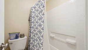 Bathroom with toilet and shower / bath combination with curtain
