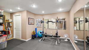 Exercise area with baseboards, a textured ceiling, and recessed lighting
