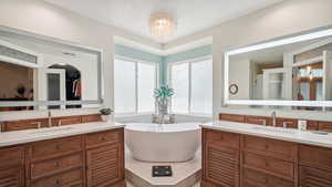 Full bathroom with two vanities, a soaking tub, and a chandelier