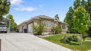 View of front of home featuring a garage, stone siding, driveway, stucco siding, and central air condition unit