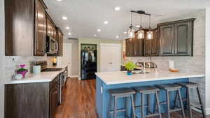 Kitchen featuring stainless steel appliances, a peninsula, a sink, tasteful backsplash, and light countertops