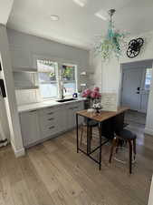 Kitchen with a sink, light wood finished floors, light countertops, a textured ceiling, and gray cabinets