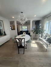 Dining room featuring a textured ceiling, wood-type flooring, a chandelier, plenty of natural light, and recessed lighting