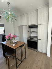 Kitchen featuring electric stove, light wood-type flooring, extractor fan, modern cabinets, and a textured ceiling