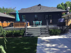 Back of property with roof with shingles, a deck, and a lawn