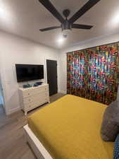 Bedroom featuring baseboards, wood finished floors, and a ceiling fan
