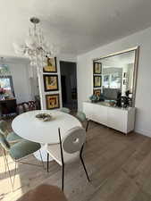 Dining space with wood finished floors, a chandelier, a textured ceiling, and baseboards
