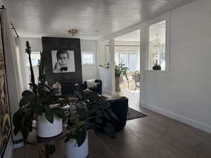 Living area featuring hardwood / wood-style flooring, a textured ceiling, baseboards, and a chandelier