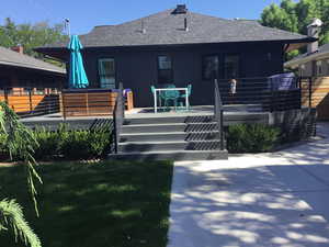Back of property with roof with shingles and a wooden deck