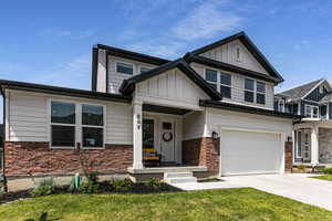 Craftsman inspired home with board and batten siding, brick siding, an attached garage, concrete driveway, and a front lawn