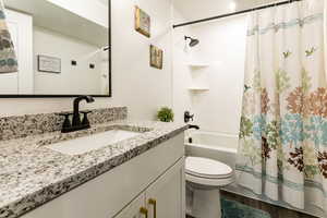 Full bath with vanity, toilet, shower / bath combination with curtain, and wood finished floors