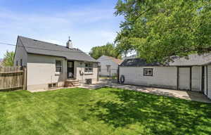 Rear view of house featuring a chimney, a patio area, stucco siding, and a shingled roof