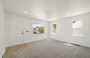 Spare room with carpet, baseboards, a textured ceiling, healthy amount of natural light, and recessed lighting