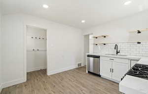 Kitchen with open shelves, dishwasher, a sink, decorative backsplash, and recessed lighting