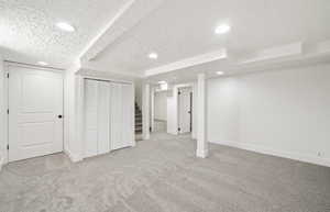 Finished basement featuring carpet floors, a textured ceiling, baseboards, and recessed lighting