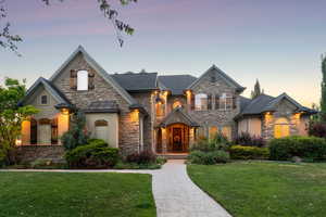 French country style house with stone siding, a lawn, and stucco siding