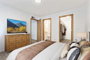 Bedroom featuring a closet, light wood-type flooring, ensuite bathroom, and baseboards