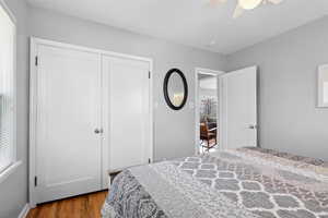 Bedroom with wood finished floors, a closet, and ceiling fan