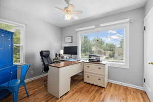 Office area with ceiling fan, baseboards, light wood-type flooring, and healthy amount of natural light
