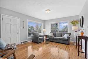 Living room with light wood-style flooring, baseboards, and a textured ceiling