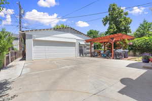 Single story home with a detached garage, a pergola, an outdoor structure, and brick siding