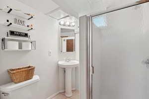 Full bath featuring toilet, a stall shower, a sink, and tile patterned flooring