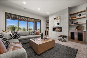 Living room with dark colored carpet, recessed lighting, and a tiled fireplace