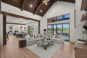 Living area featuring light wood-type flooring, high vaulted ceiling, a mountain view, wooden ceiling with exposed beams, and recessed lighting