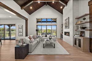 Living room featuring high vaulted ceiling, a fireplace, light wood-style floors, wooden ceiling with exposed beams, and recessed lighting
