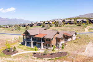 Rear view of house with a balcony, stone siding, a mountain view, and a residential view