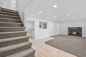 Below grade area with stairway, recessed lighting, a premium fireplace, carpet flooring, and baseboards
