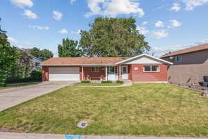 Single story home featuring brick siding, an attached garage, concrete driveway, and a front yard