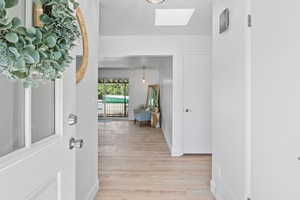 Foyer featuring a skylight, light wood-style floors, and baseboards