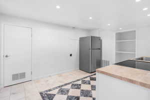 Kitchen with freestanding refrigerator, recessed lighting, butcher block counters, electric range oven, and a sink