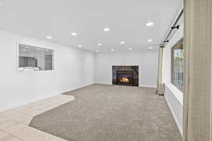 Unfurnished living room with recessed lighting, a fireplace, carpet flooring, tile patterned floors, and baseboards