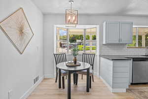 Dining room with baseboards, light wood-style flooring, a chandelier, and a textured ceiling