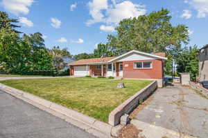 View of front facade featuring brick siding, driveway, a front yard, and a garage