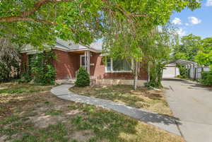 View of front facade with brick siding, a garage, driveway, and a carport