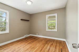 Spare room with healthy amount of natural light, wood finished floors, and baseboards