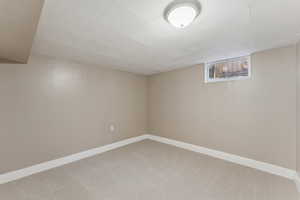 Basement featuring light carpet and baseboards