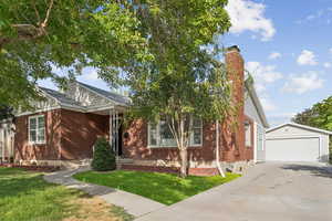 View of front of property with an outbuilding, a chimney, a detached garage, and brick siding