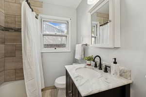 Full bath featuring vanity, shower / bath combination with curtain, and light wood finished floors