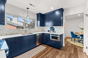 Kitchen featuring stainless steel appliances, blue cabinets, a sink, light countertops, and recessed lighting